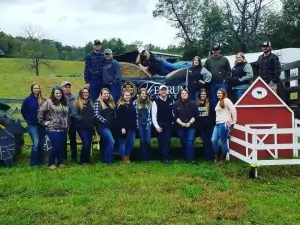 A group of people standing in a field next to a small structure