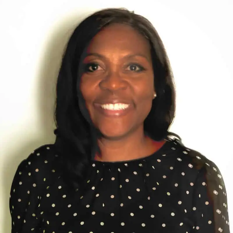 Head shot of Angela Payne against white background with long dark hair and black patterned shirt