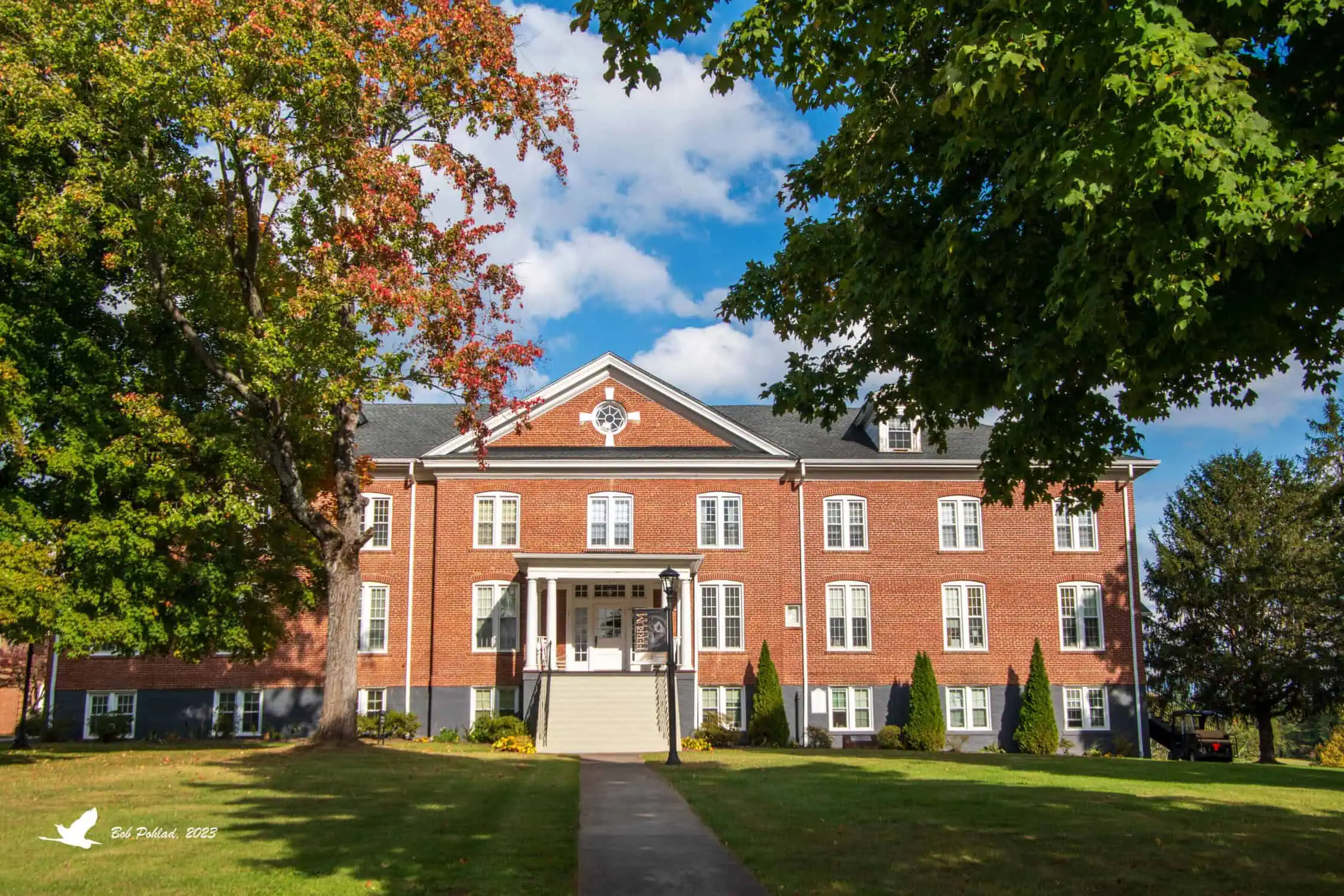 John Wesley Hall at Ferrum, brick classical building with white trim, porch, and steps, with trees and grass framing