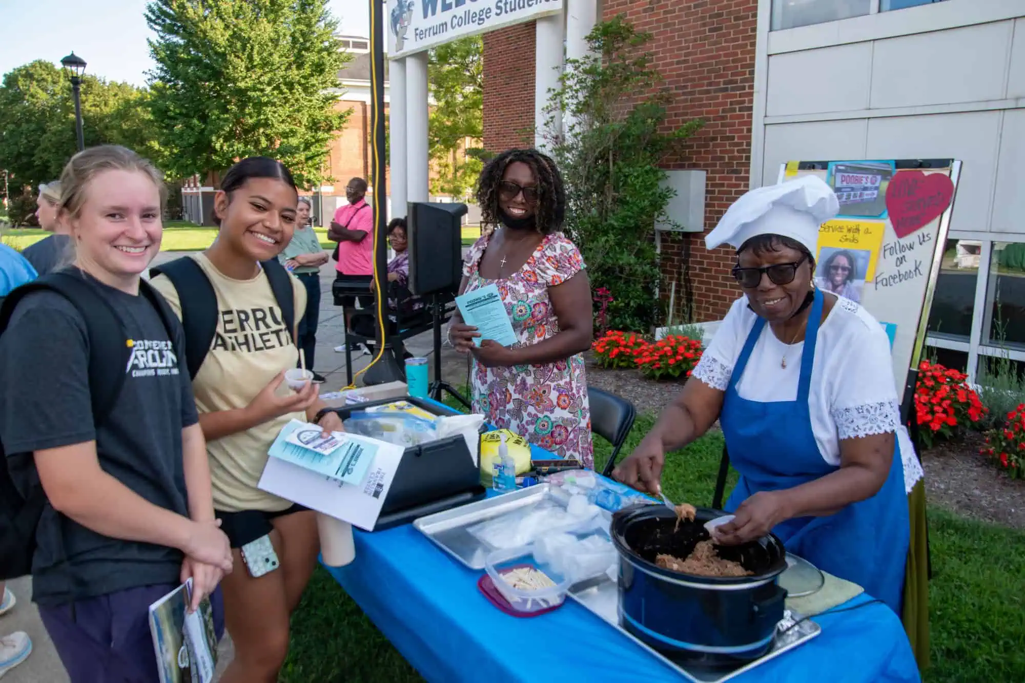 Two Ferrum College students are receiving a sample of barbecue from two women from Poobie's Kwik Stop