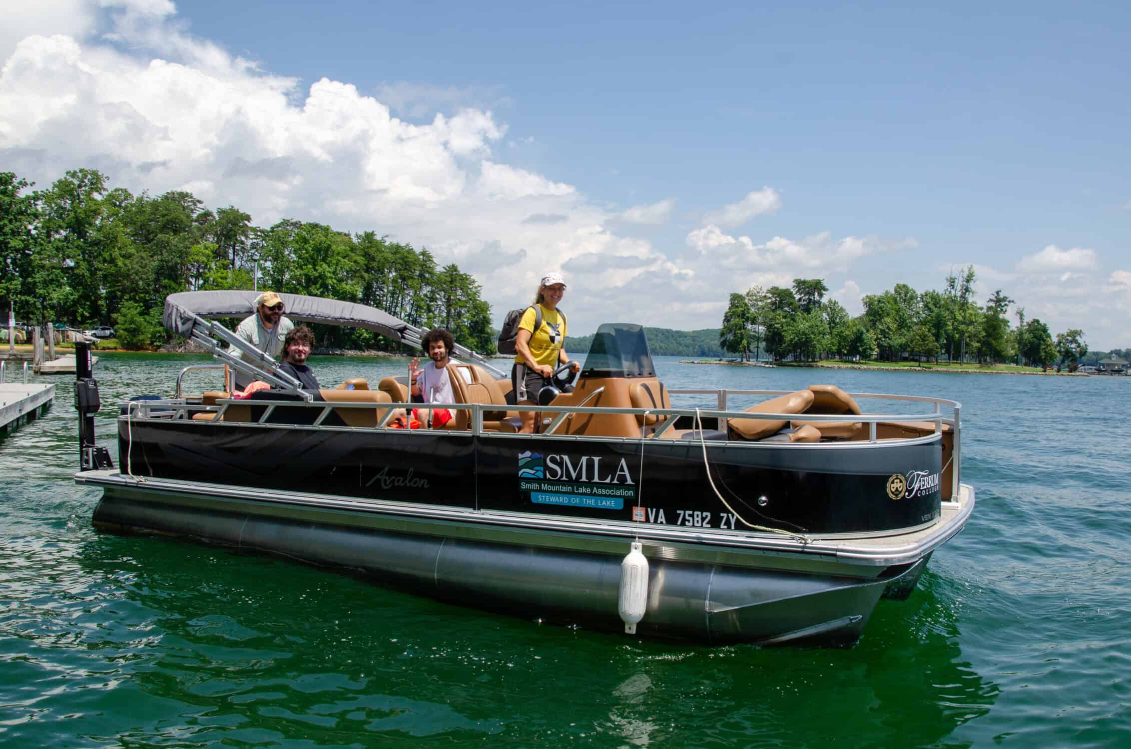 Smith Mountain Lake Water Quality team on the Ferrum College boat on the lake with blue sky and puffy white clouds