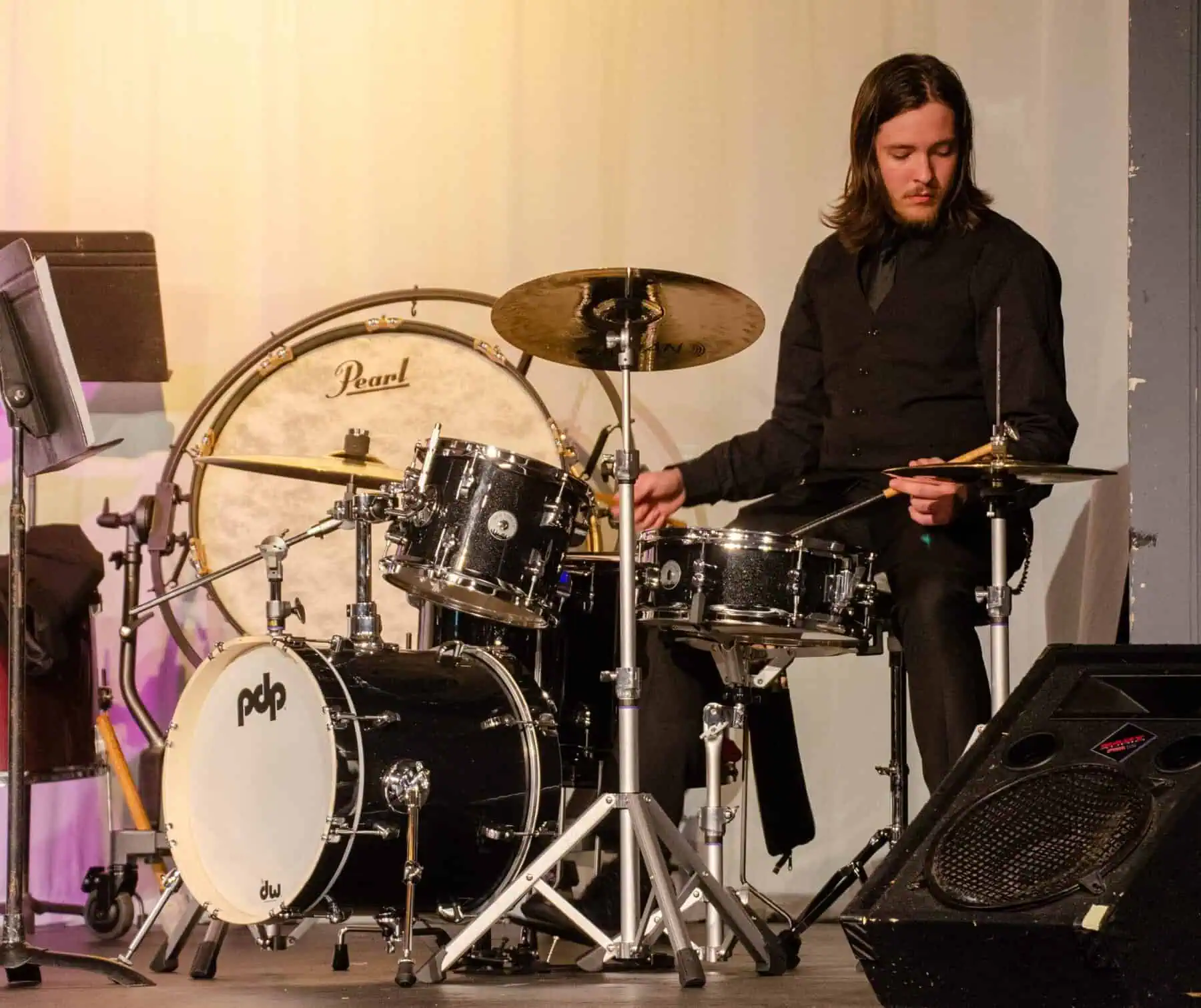 male percussionist playing drum set at band showcase in theatre spring 2023