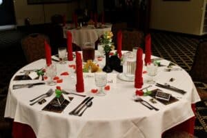 Tables set for Sweetheart Society Valentine's event, with white tablecloths, red candles, black and red decorations