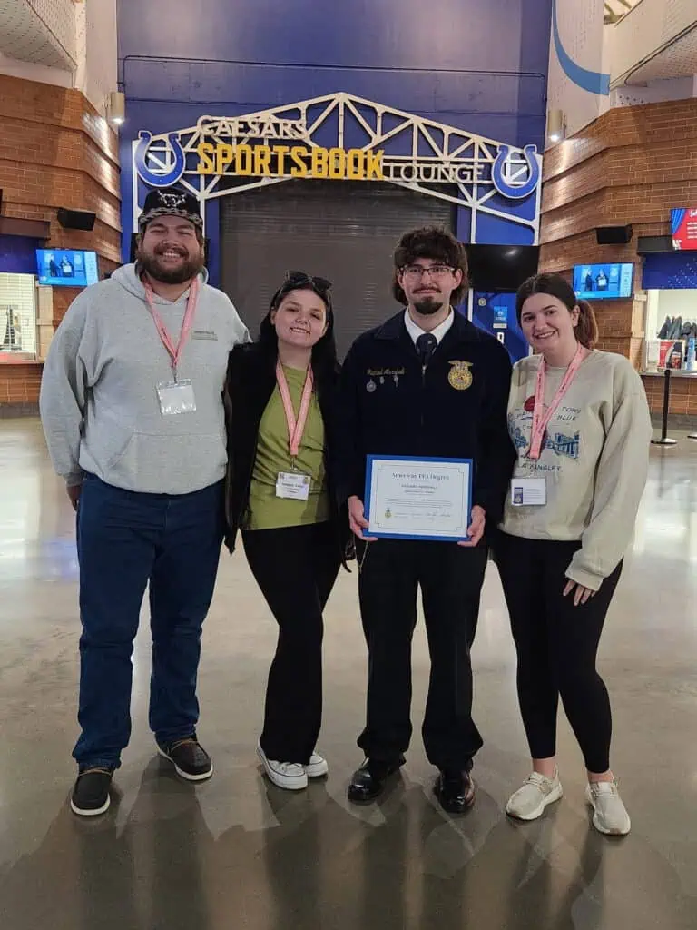Four Ferrum College students at FFA Convention, including honoree Richard Marshall holding certificate