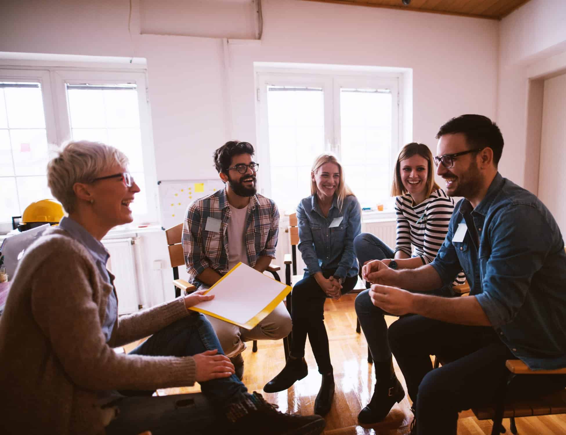 group of people in a circle smiling talking to a female instructor