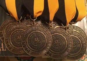 Photo of a group of Ferrum College Boone Honor Program bronze medallions hanging from the ends of gold and black ribbons