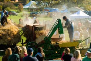 An antique hay making machine in action as people look on