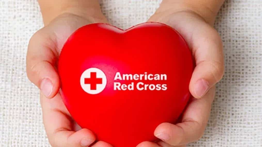 Blood drive graphic with two photographed hands holding a heart-shaped object that says American Red Cross