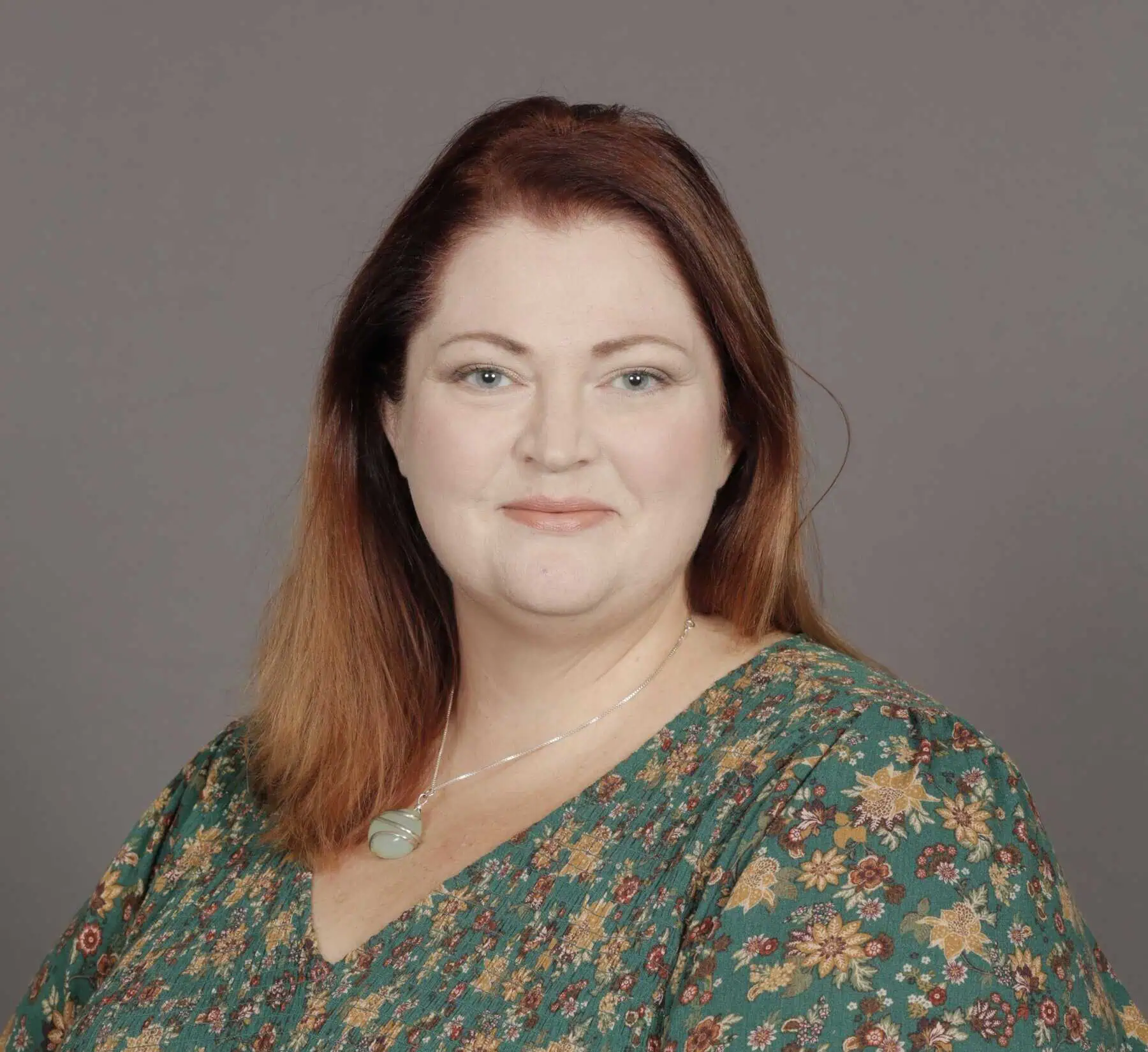 Head shot of Brooke Gill with green patterned shirt and green stone necklace