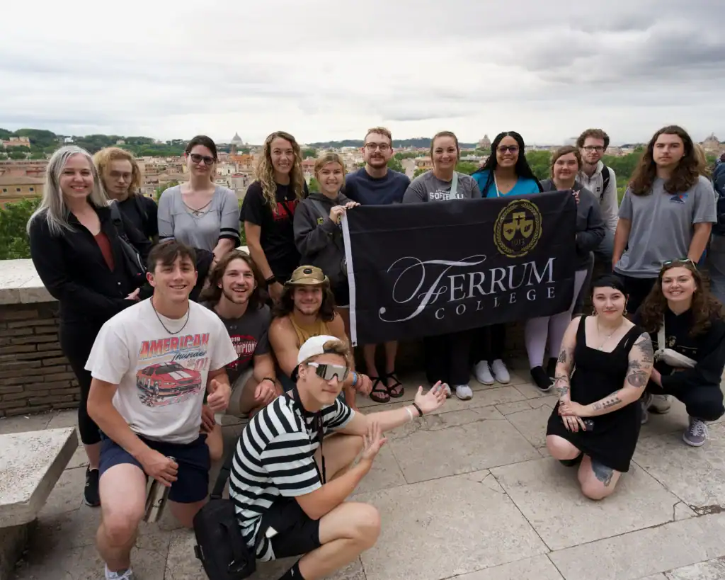 17 Ferrum College students posed for a photo holding a Ferrum College flag in Florence, Italy