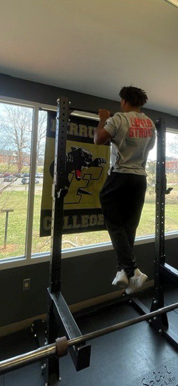 Ferrum College student doing a pull up in front of a Ferrum Flag featuring the panther logo. 