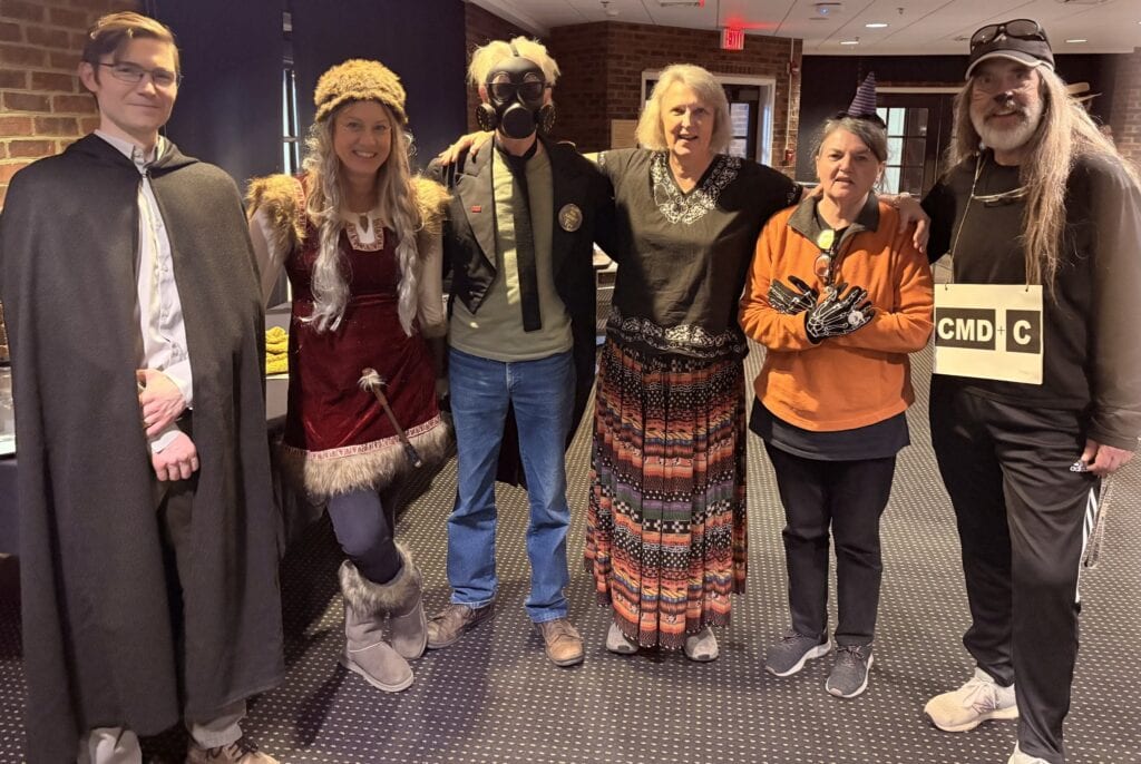 Six English faculty members in varied costumes at 2024 Ferrum College coffee house