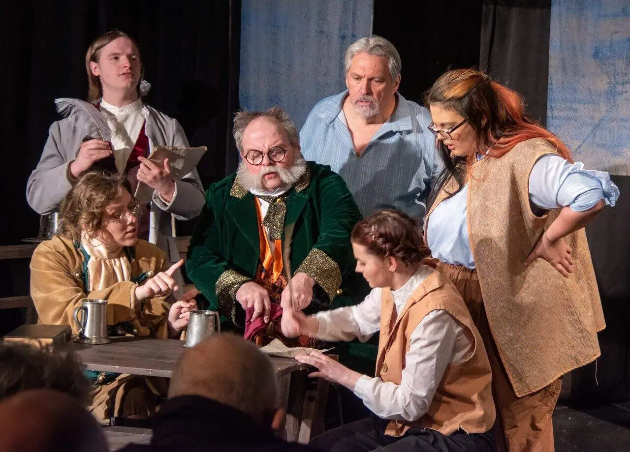 Image is of theatre arts cast in a production of Treasure Island. Dressed in full 18th century costume.