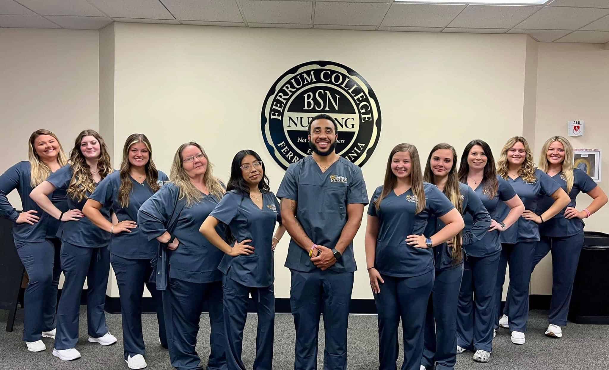 Elleven nursing students standing in a V formation wearing scrubs