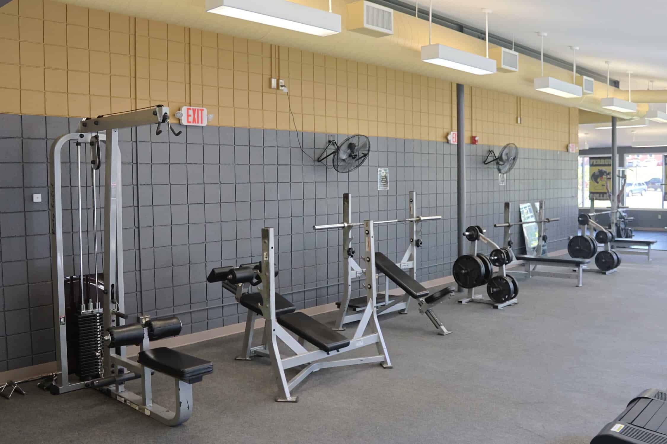 A lat pull down machine, a decline, incline, and flat bench all lined up to the left. There are weight racks in between the incline and flat bench.