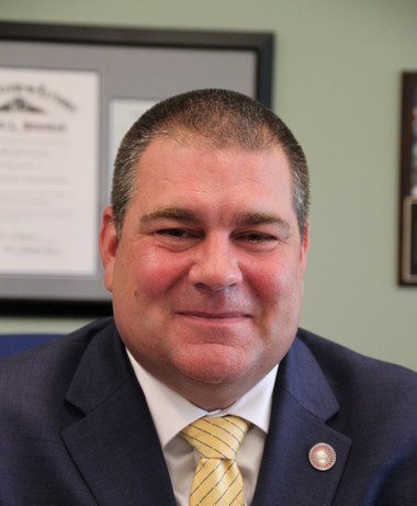 Headshot of Jamie Green, Board of Trustees, in a suit with a light striped tie.
