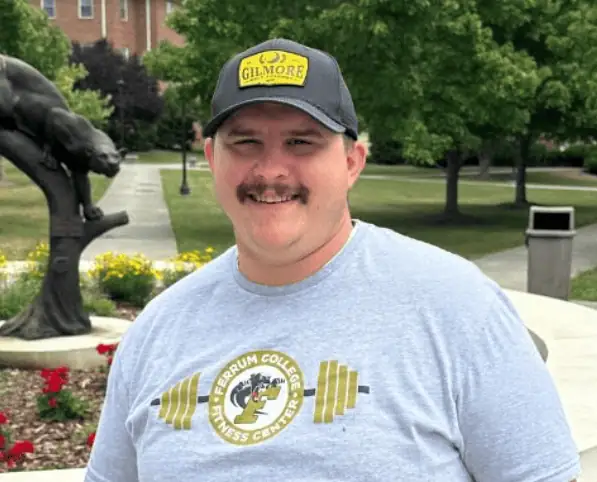 Head shot of Jimmy Sturgill '16 in grey Ferrum t-shirt and dark ball cap with panther statue in background