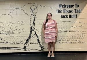 Logann Gavey in striped dress at white Jack Tale wall in Rex Stephenson Theatre