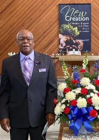 Dr. Melvin Macklin in a suit with flowers and a banner in Vaughn Chapel at Ferrum College