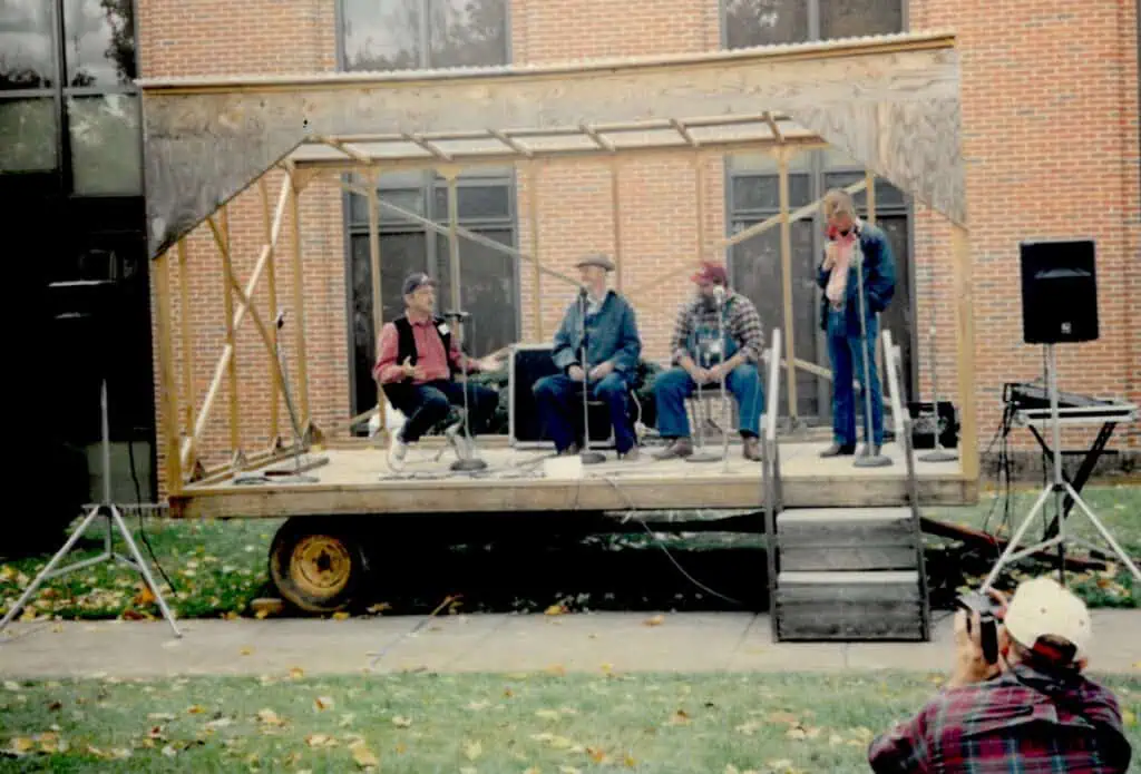 Small outdoor stage at the Blue Ridge Folklife Festival in October 1995 with Rex Stephenson standing right and storytellers Ray Hicks (center) and Orville Hicks between them.