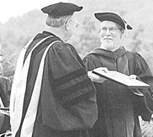 Yearbook photo of Pete Crow receiving teaching award from Ferrum College President Jerry Boone at graduation, with both  wearing academic robes.