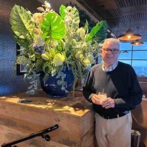 Alumnus Herb Pettway in dark sweater with a large  floral creation.