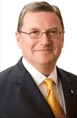 Headshot of Baxter Phillips in a dark suit and gold tie
