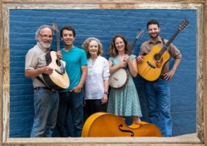 The Robeys, family band with five members standing in a row against a deep blue background with a frame that looks like wood around the graphic. They wear tan, white, and turquoise clothes, holding guitars, and banjo with a bass at the bottom.