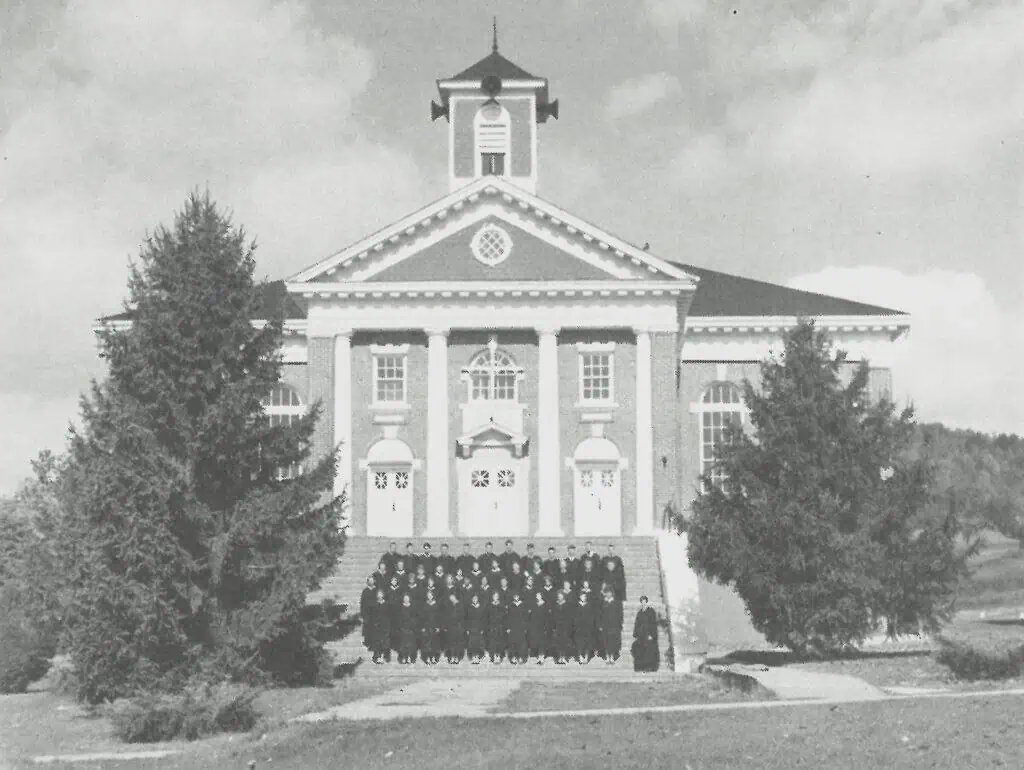 Schoolfield Hall in 1977 Ferrum College history book with graduates in black robes on front steps