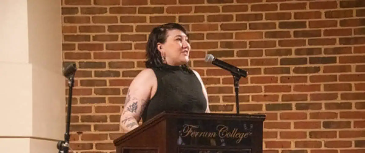 Student in black outfit at Ferrum College podium in front of brick wall