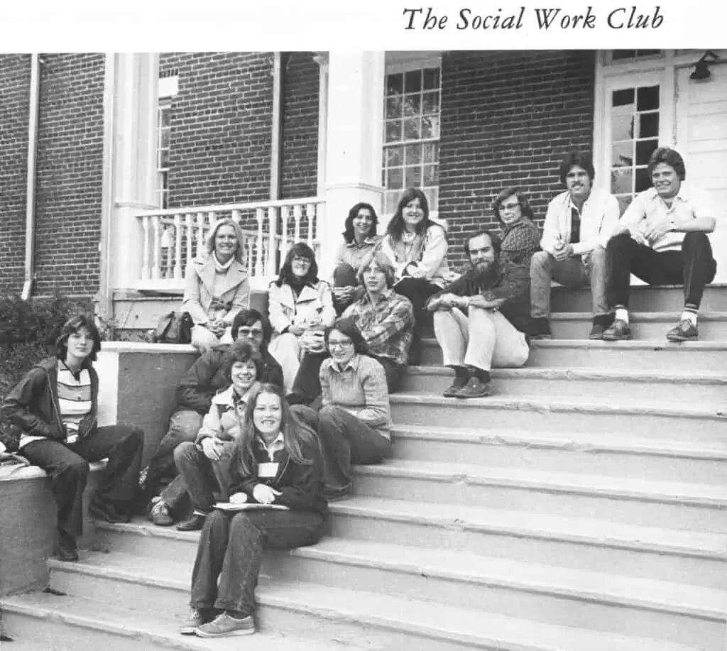 Black and white 1978 yearbook photo of The Social Work Club, 14 students in casual clothes sitting on tall steps of Roberts Hall