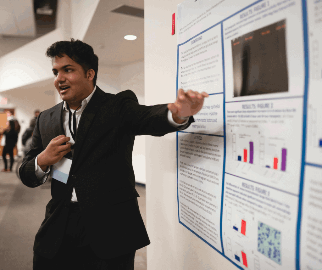 Young man in a suite presenting a research board.