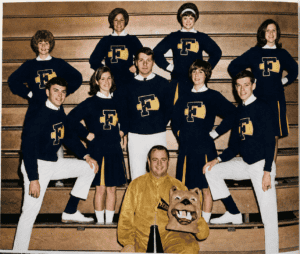 Six female and 3 male cheerleaders pose in black, gold, and white outfits with a capitalized F on their sweatshirts. A male mascot in gold sits at the bottom.
