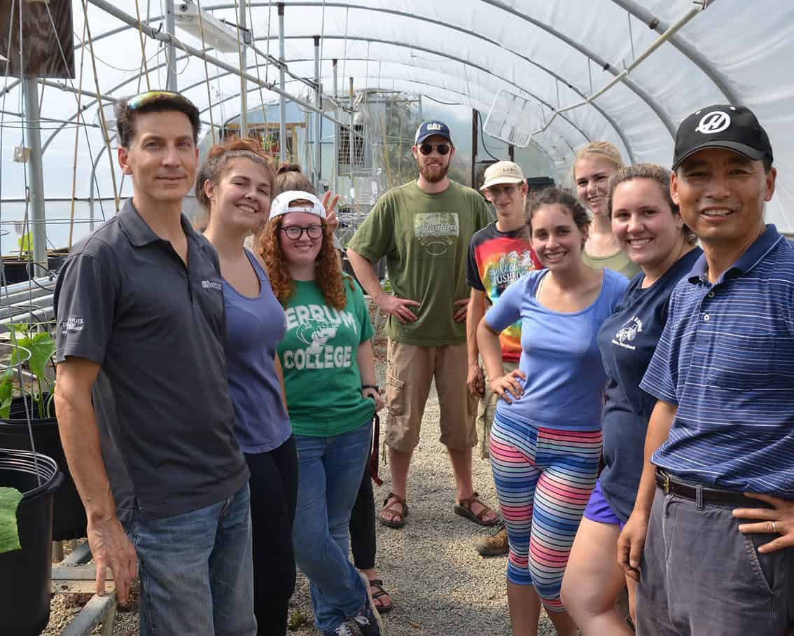 A group of people smiling and posing in the greenhouse
