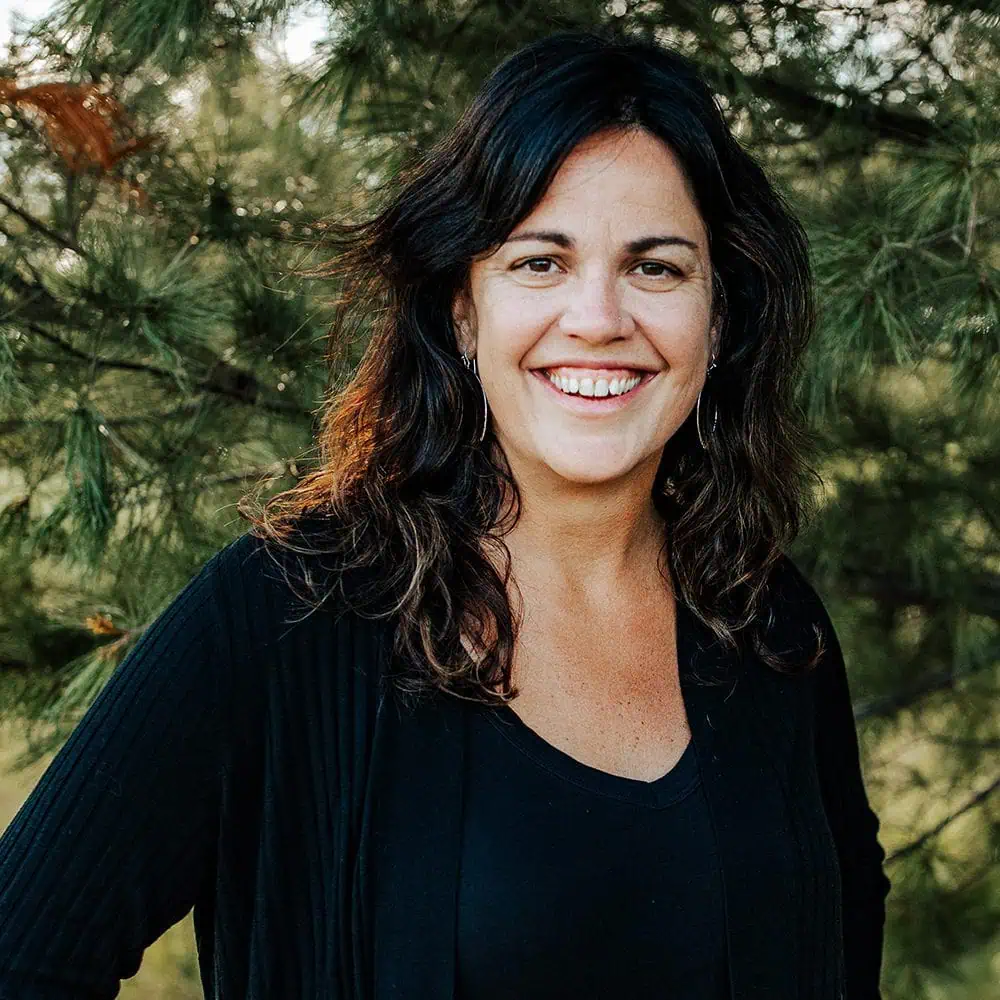 Staff Headshot of Angie Dahl standing outside in front of a tree.