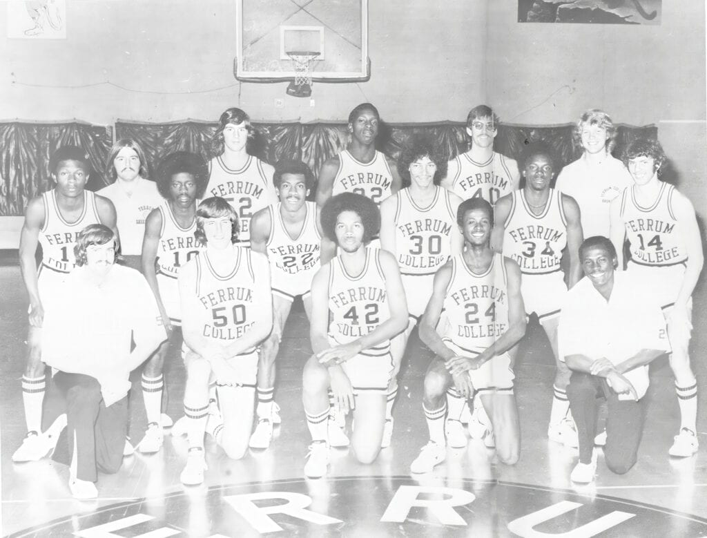 Black and white yearbook photo of 1974-75 basketball team with 16 young men posed in rows in a basketball court.