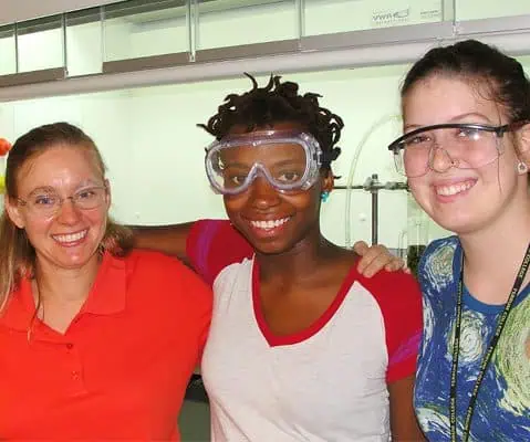three female students wearing protection goggles in classroom