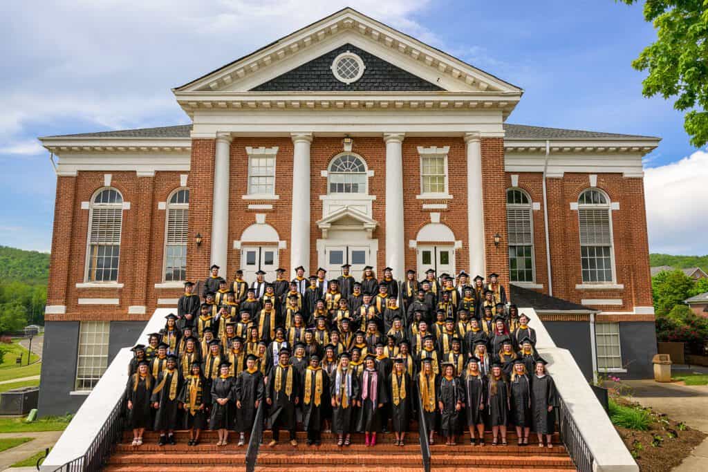 The Ferrum College class of 2025 pictured in full regalia on the steps of Schoolfield Hall. 