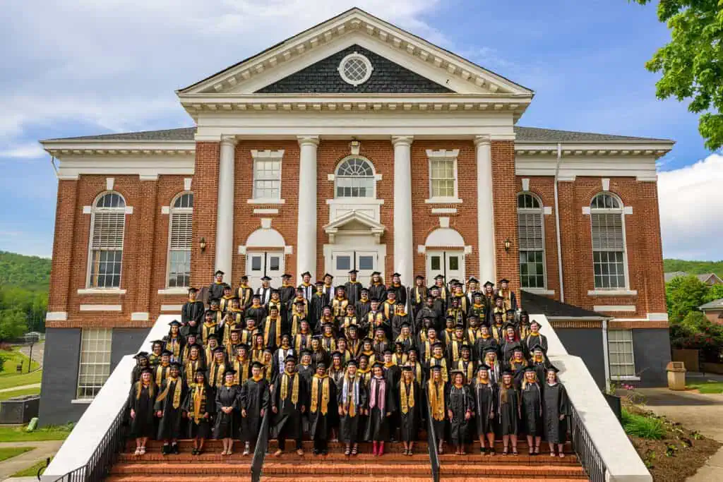 The Ferrum College class of 2025 pictured in full regalia on the steps of Schoolfield Hall.