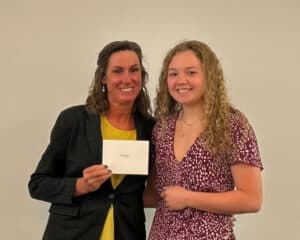 Two women stand together at the Boone Honors Banquet 2026, holding an award certificate in front of a large screen backdrop.