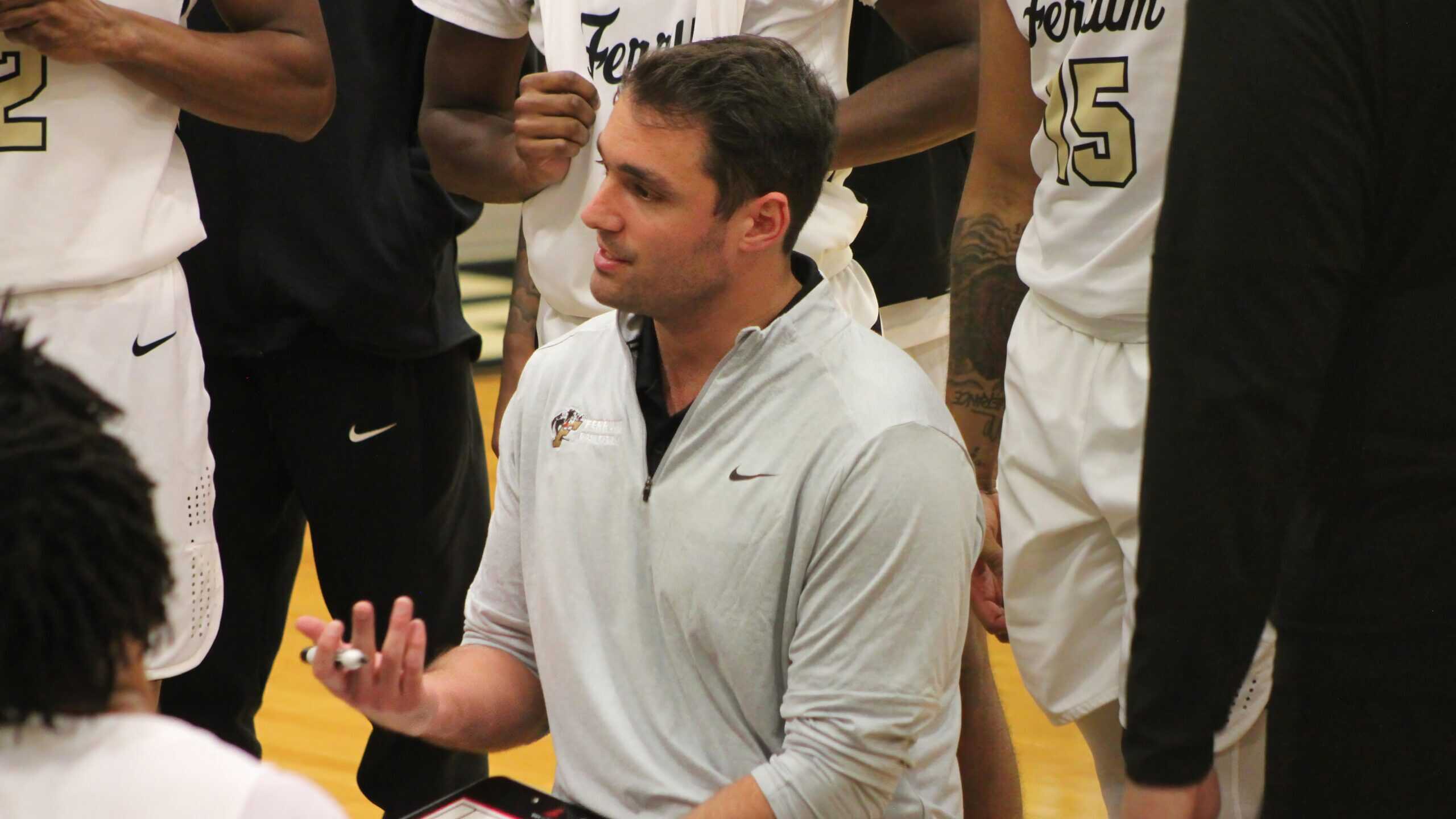 Male basketball coach giving instructions while surrounded by his players