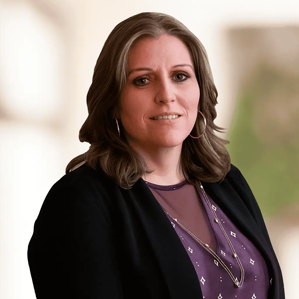 Headshot photo of Michelle Chapman who has shoulder length brown hair and who is wearing a black blazer of a purple patterned blouse