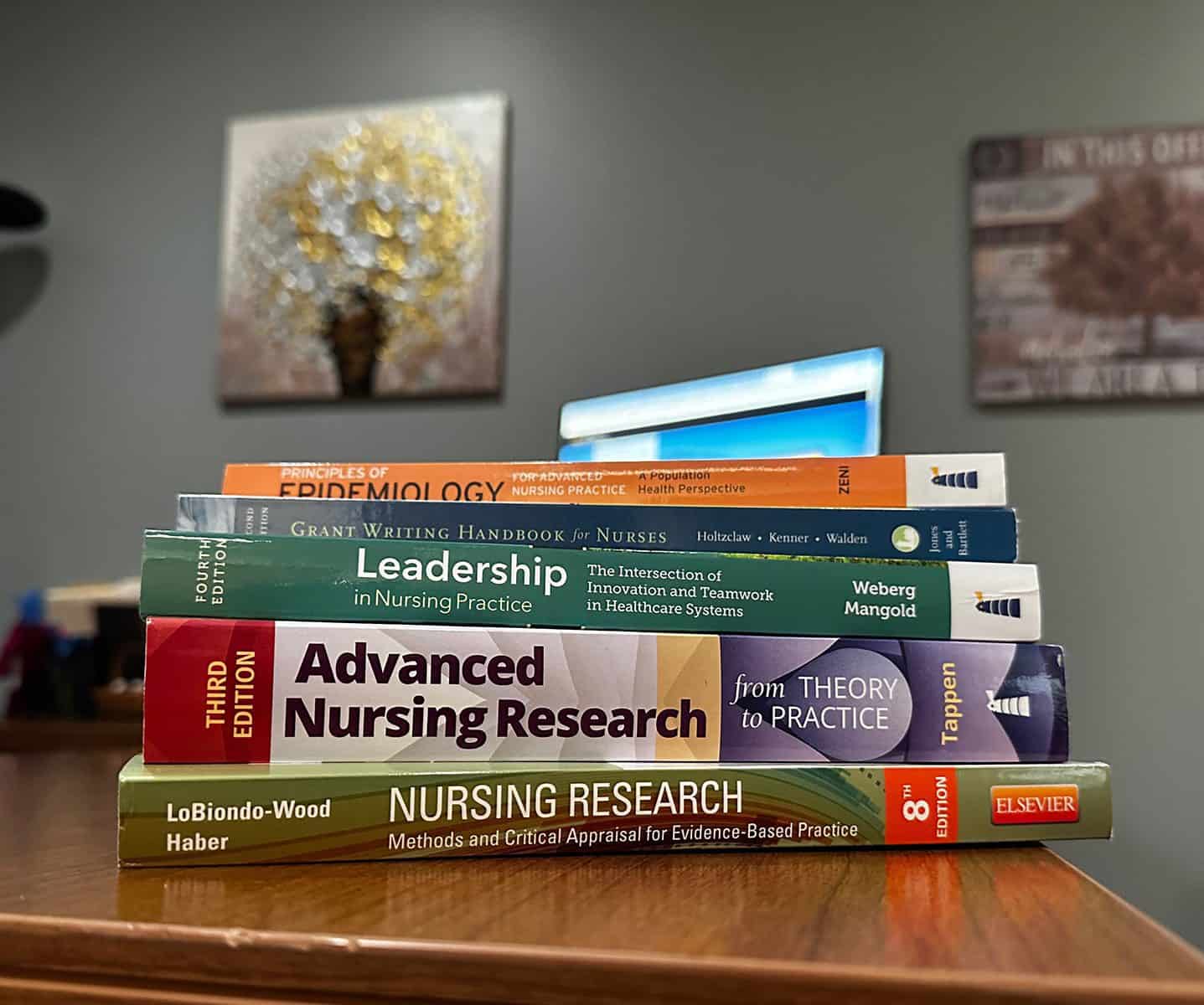Stack of books used in the MSN program at Ferrum College on a desk