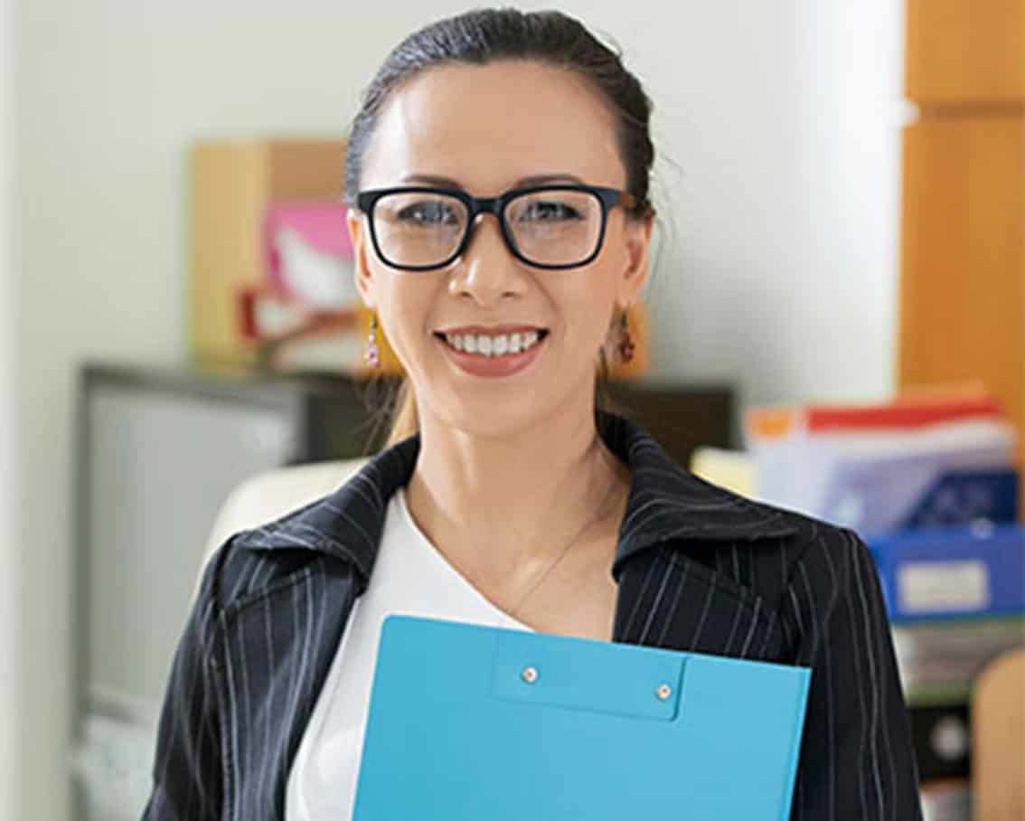 Woman standing holding a blue folder.