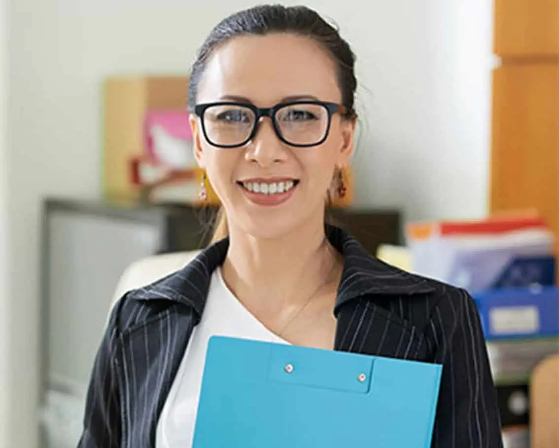 Woman standing holding a blue folder.