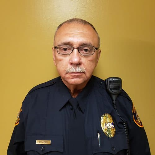 officer john acord in uniform and glasses in front of yellow background for staff photo
