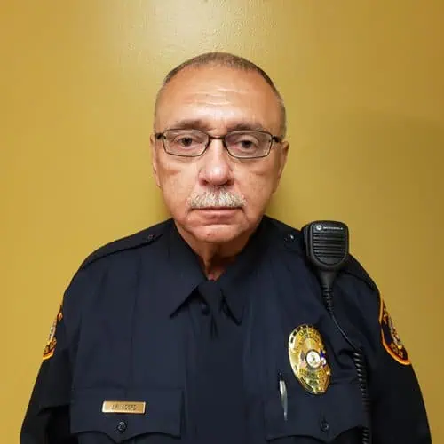 officer john acord in uniform and glasses in front of yellow background for staff photo