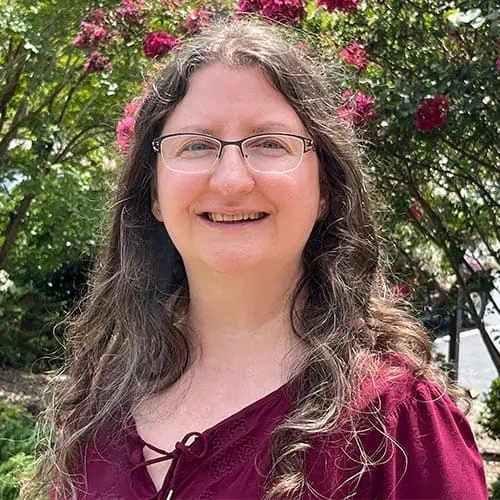 Headshot of Ferrum College staff Dawn Kessler standing outside in front of floral bush.
