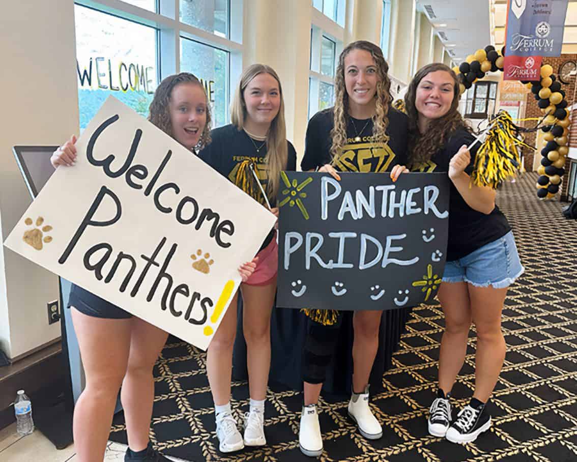 Students standing in Franklin Hall holding signs welcoming new students at orientation.