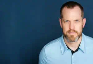 Dan McClellan wearing a blue shirt with a blue background